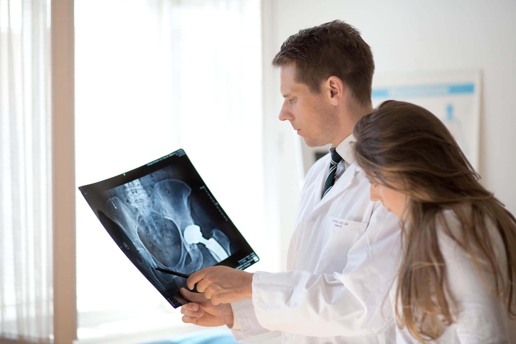 Ärzte im weißen Kittel analysieren ein Röntgenbild im Krankenhaus, besprechen medizinische Ergebnisse.