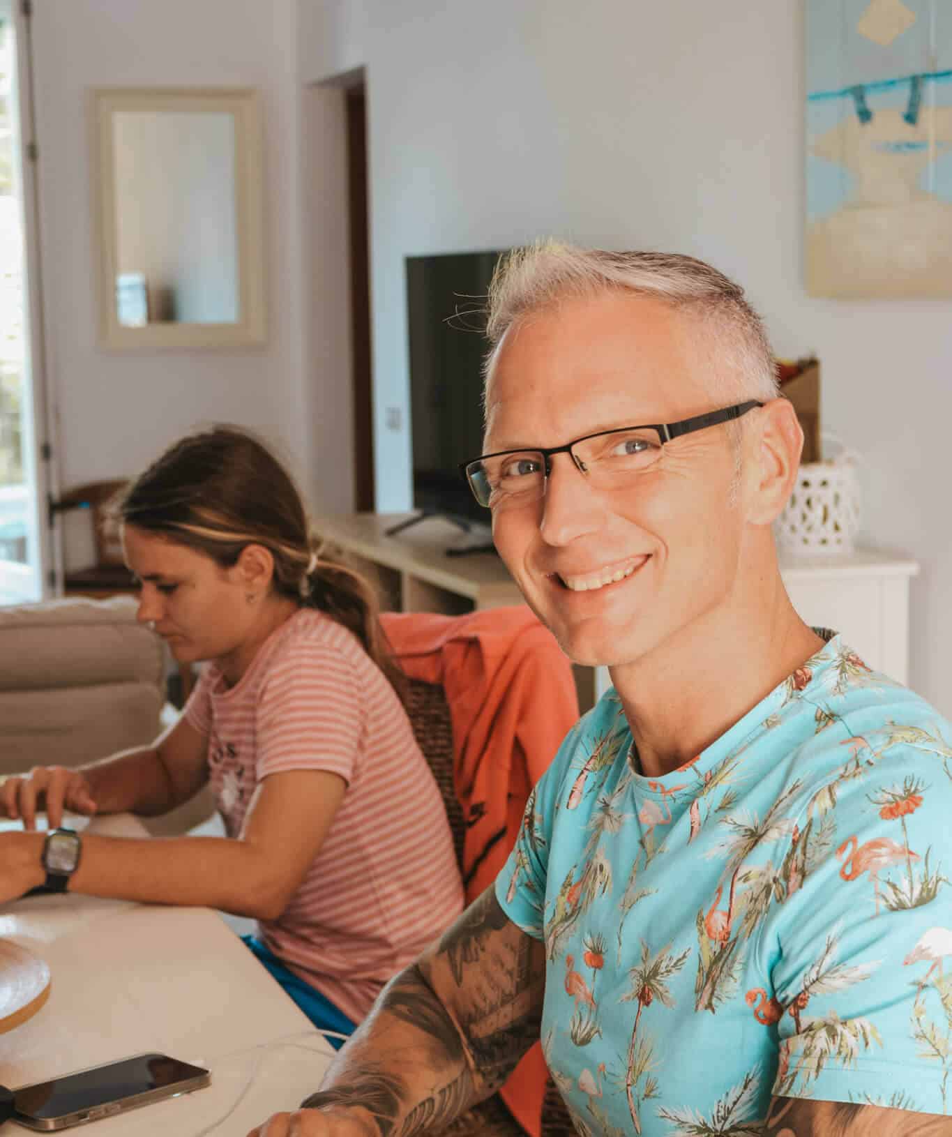 Personen arbeiten am Tisch an Computern, lächelnder Mitarbeiter im Vordergrund, Büro der WordPress-Agentur Webschmiede.