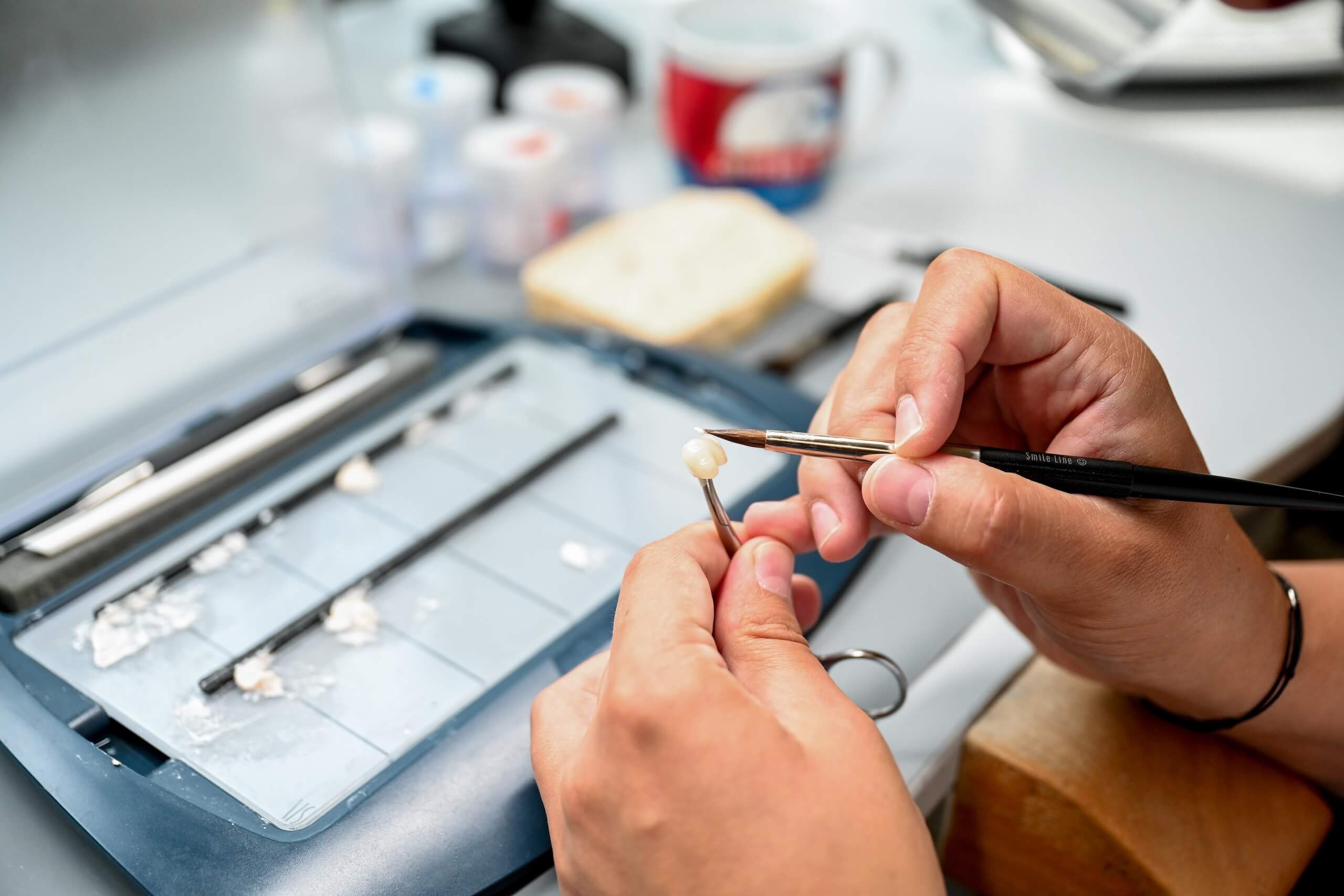 Person modelliert mit Werkzeugen ein Zahnmodell in einem Labor-Setting.