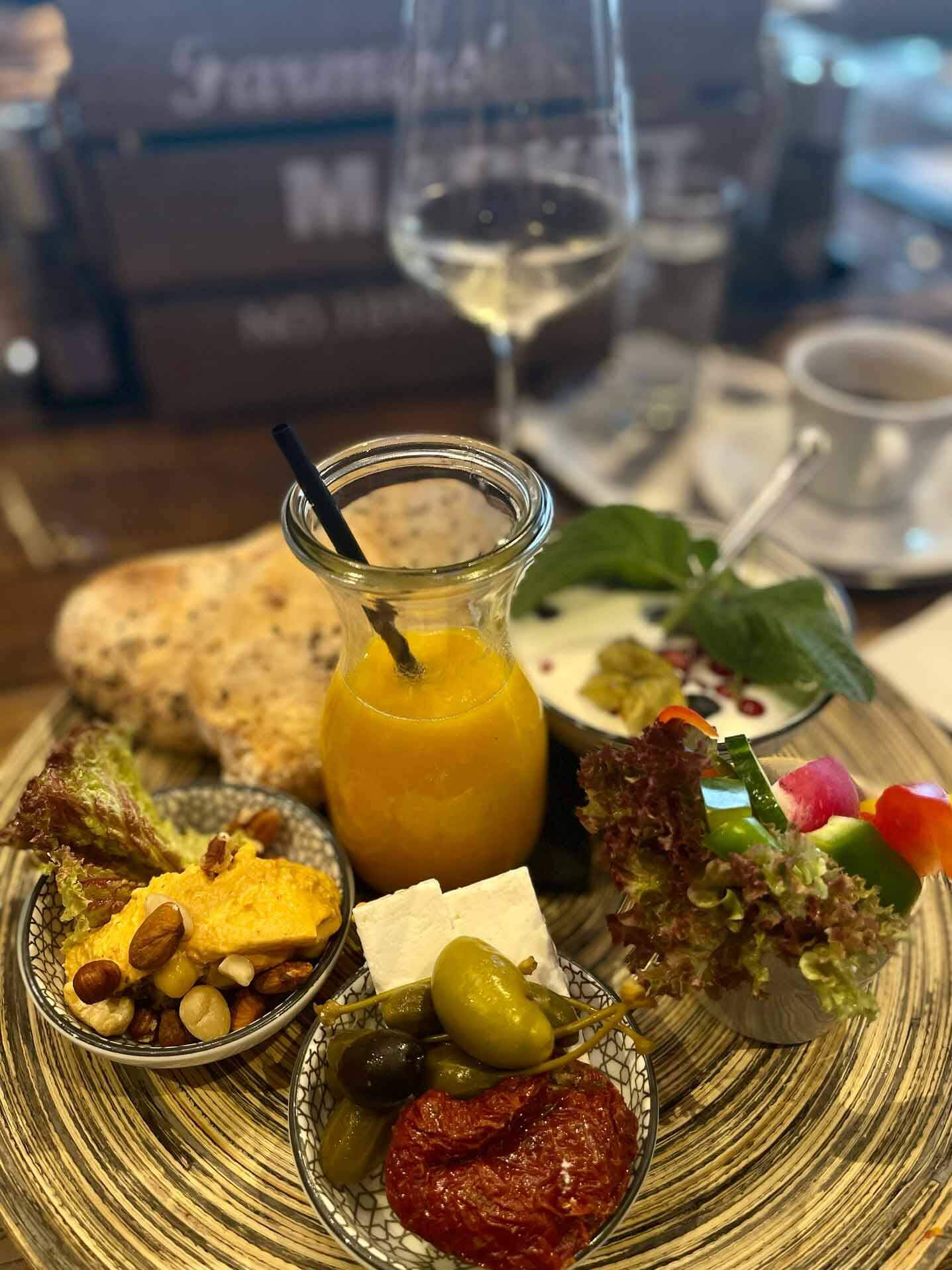 Vielzahl von Frühstücksdelikatessen mit Orangensaft, Brot und Gemüse auf einem Tisch in gemütlichem Ambiente.