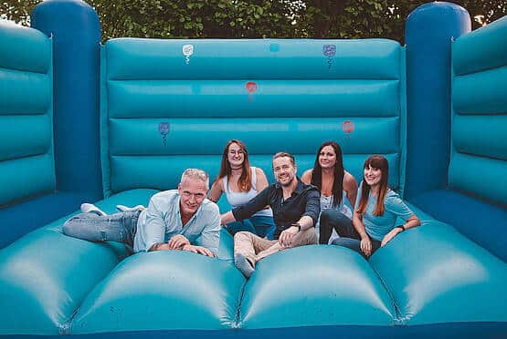Eine Gruppe von Menschen entspannt auf einer Hüpfburg, Teamaktivität der Webschmiede-WordPress-Agentur Oberwart.