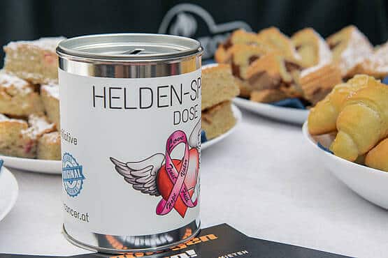 Spendenbox mit Flügel-Design, umgeben von Gebäck auf einem Tisch bei Webschmiede-Event, Oberwart.