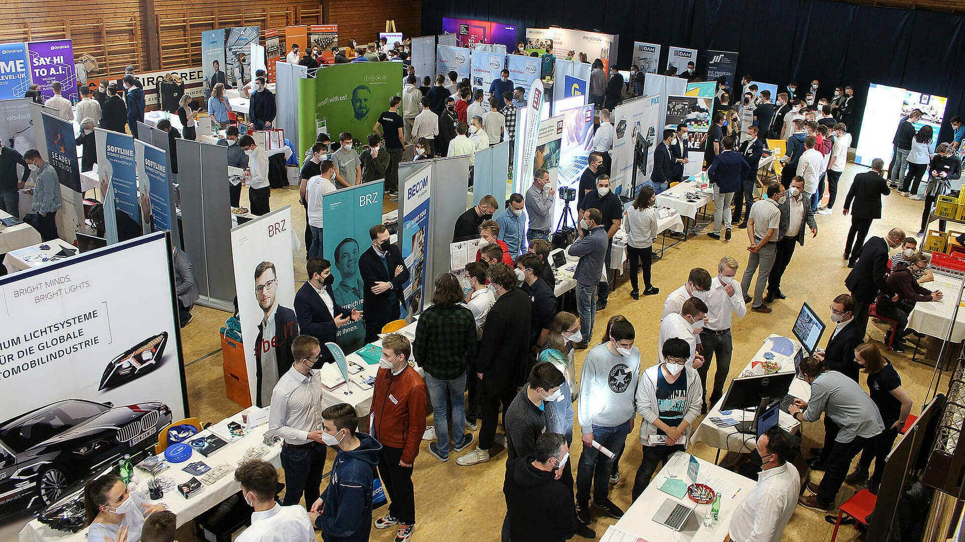 Menschenmenge besucht eine Fachmesse mit Ständen zu Webdesign, WordPress, Webshops und SEO in einer Halle.