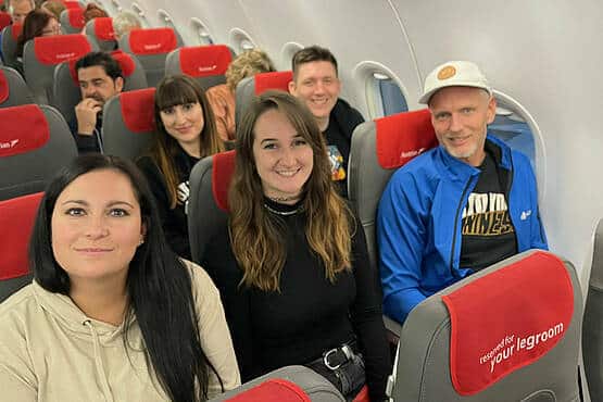 Personengruppe sitzt entspannt in Flugzeugsitzen, Blick nach vorne gerichtet, Teil einer Reise der Webschmiede-Agentur.
