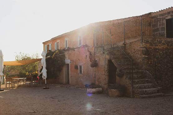 Mediterranes Landhaus aus Stein mit Sonnenschirm und Außenterrasse in der Abendsonne, geeignet für Webdesign-Projekte.