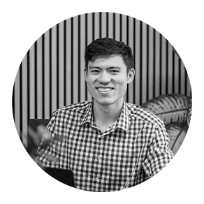 Mitarbeiter der Webschmiede sitzt lächelnd im Büro, umgeben von Pflanzen und gestreifter Wand, vermittelt moderne Arbeitsatmosphäre.