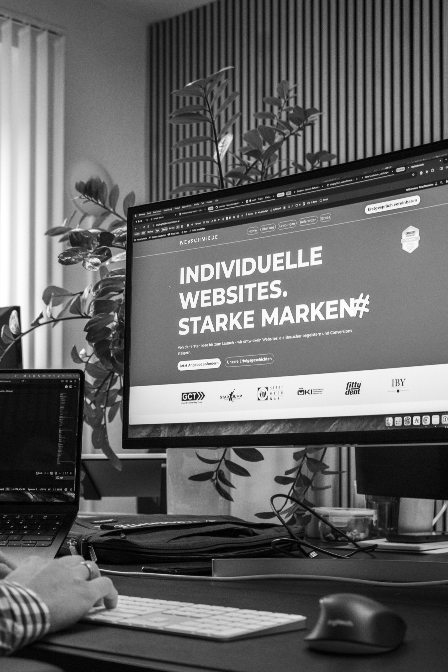 Eine Person arbeitet am Computer, der Bildschirm zeigt eine WordPress-Agentur-Seite mit dem Slogan „Individuelle Websites. Starke Marken“.