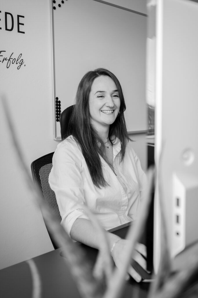 Eine Person arbeitet lächelnd an einem Computer im Büro der Webschmiede WordPress Agentur in Oberwart.