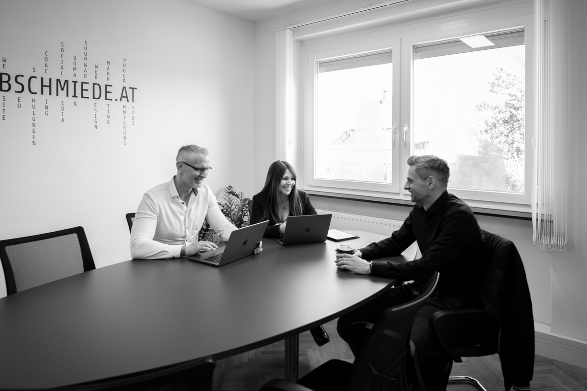 Team in Besprechung bei der Webschmiede, WordPress-Agentur, mit Laptops in modernem Büro in Oberwart.