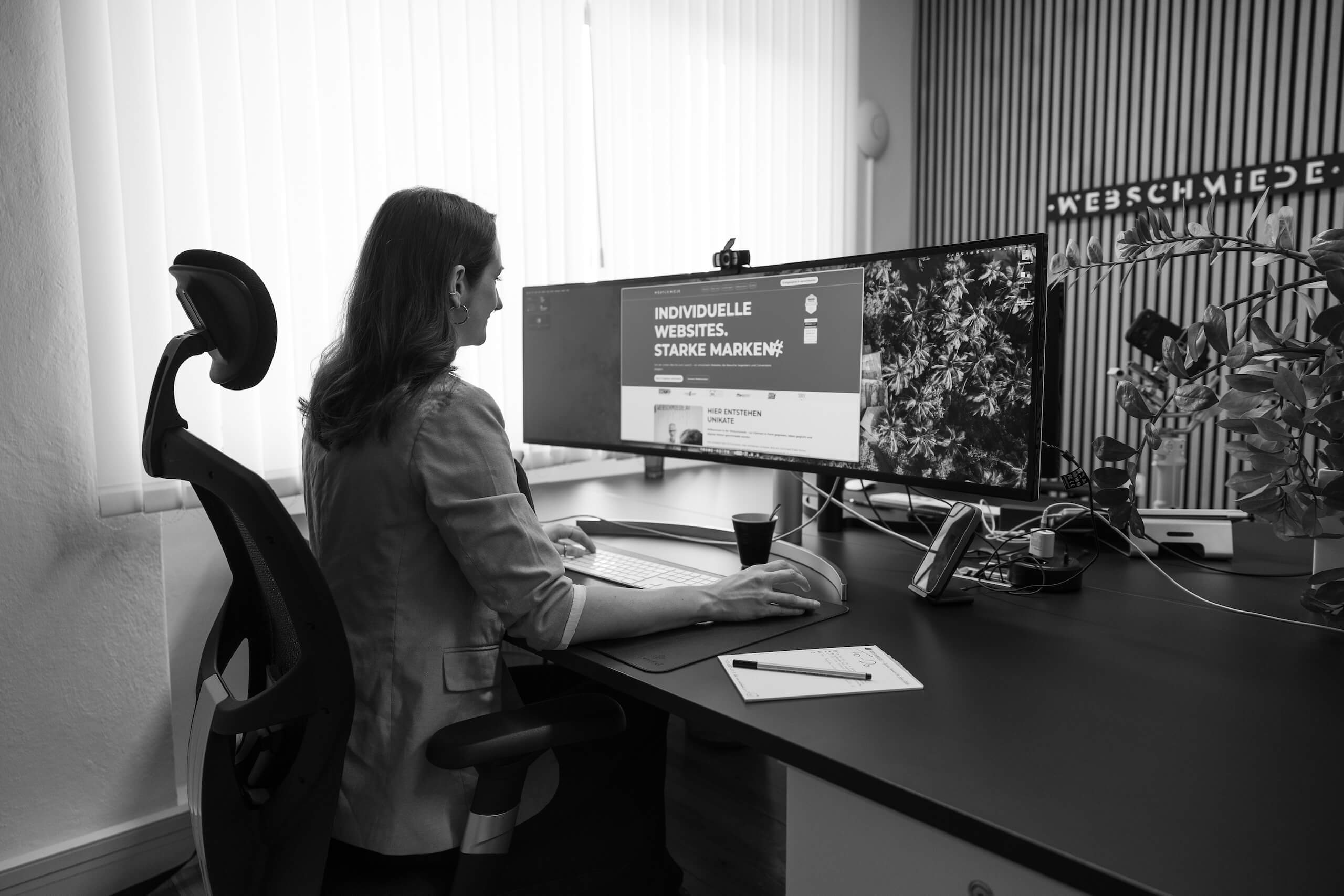 Eine Person arbeitet am Computer in der Webschmiede, zeigt eine WordPress-Website mit „Individuelle Websites, starke Marken“.