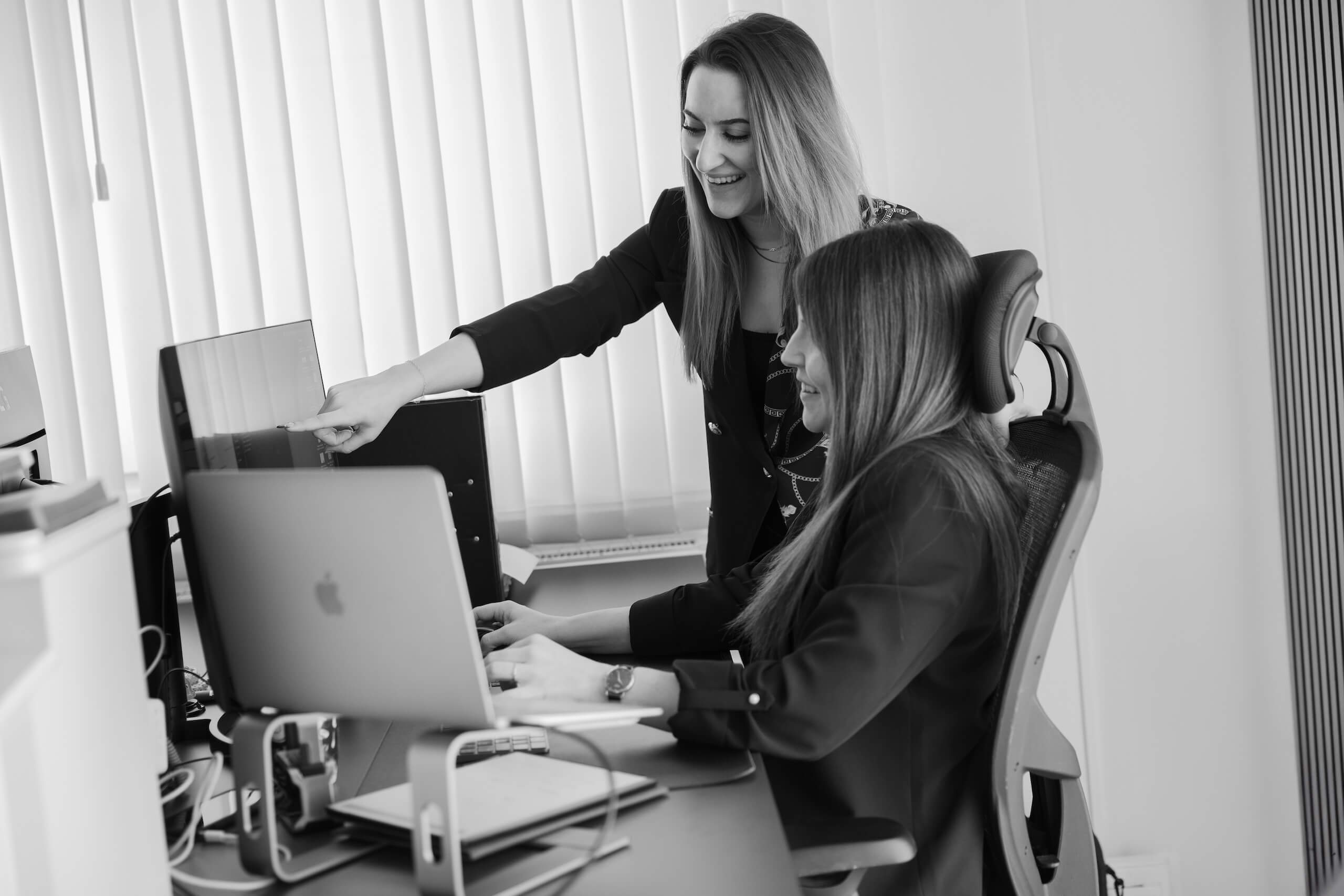 Zwei Mitarbeiterinnen der Webschmiede arbeiten an einem Computerbildschirm im Büro einer WordPress- und SEO-Agentur.