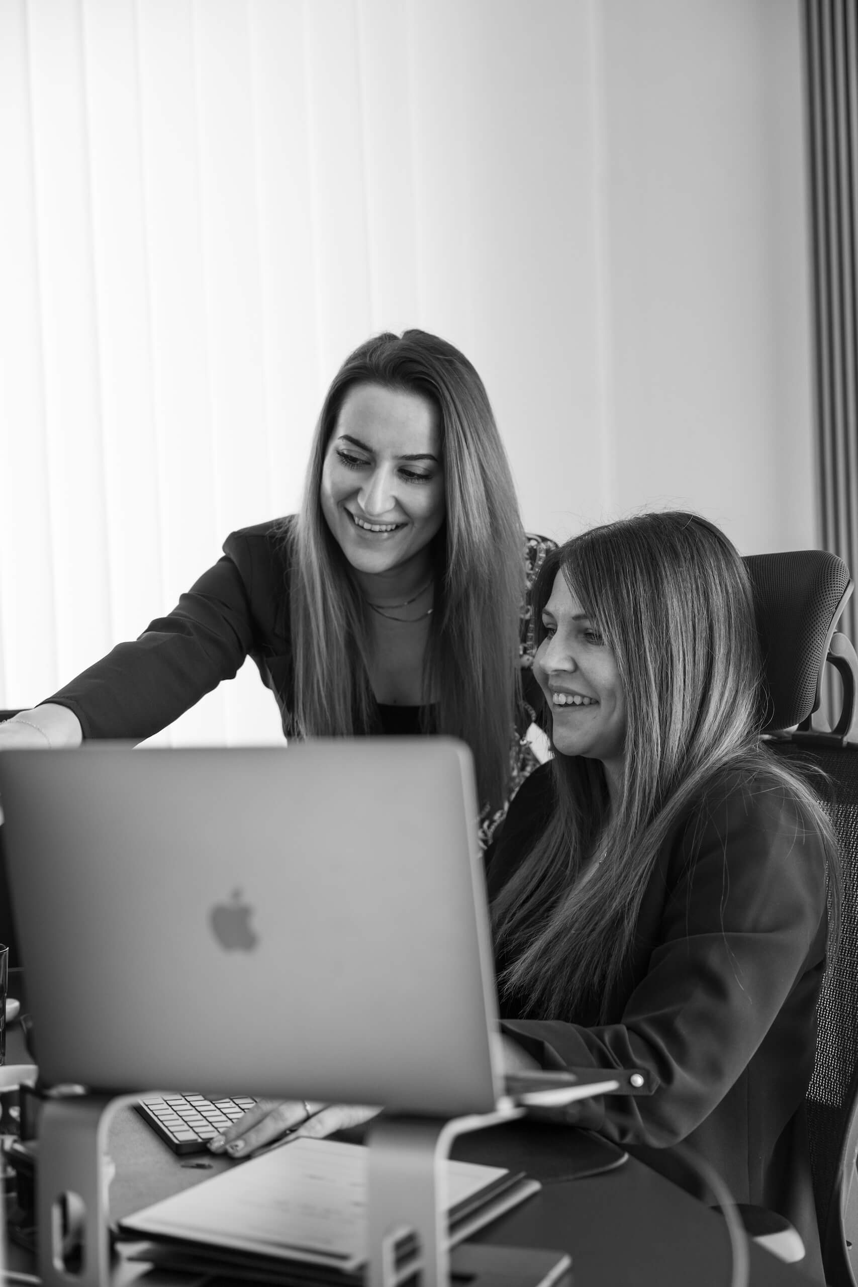 Zwei Mitarbeiterinnen der WordPress-Agentur arbeiten zusammen an einem Laptop im Büro der Webschmiede.