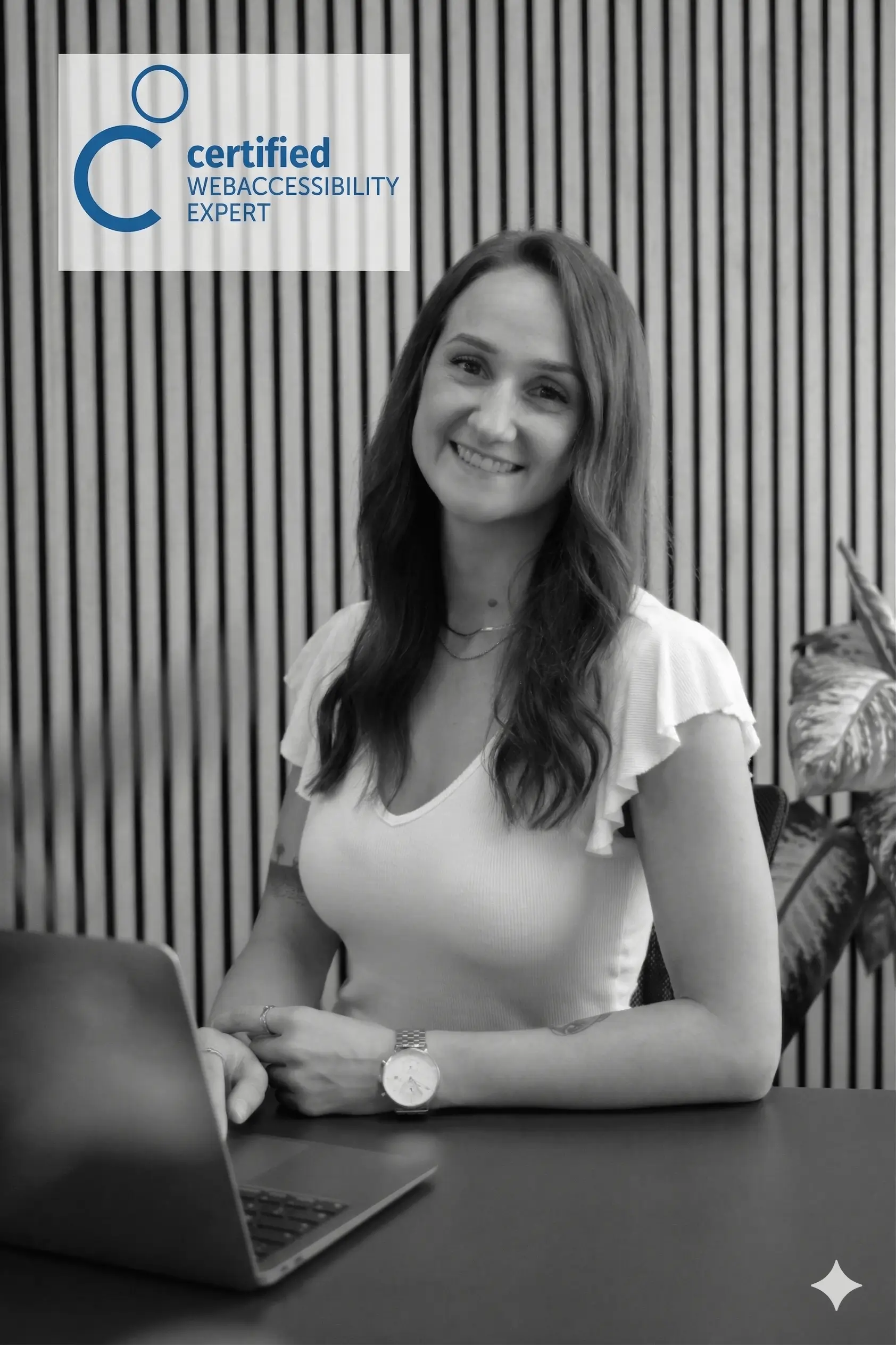 Eine Person arbeitet an einem Laptop im Büro, mit einem Zertifikat für Webzugänglichkeit im Hintergrund.