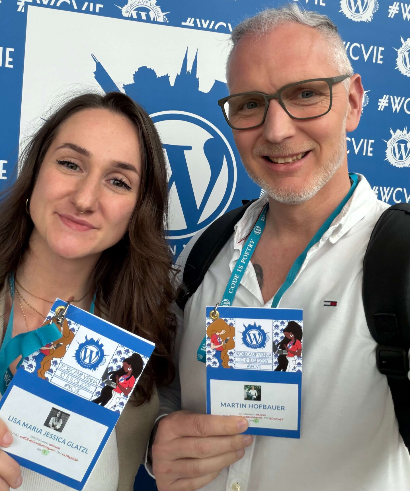 Teilnehmer auf einer WordPress-Konferenz, halten Namensschilder, vor WordCamp Vienna Hintergrund.