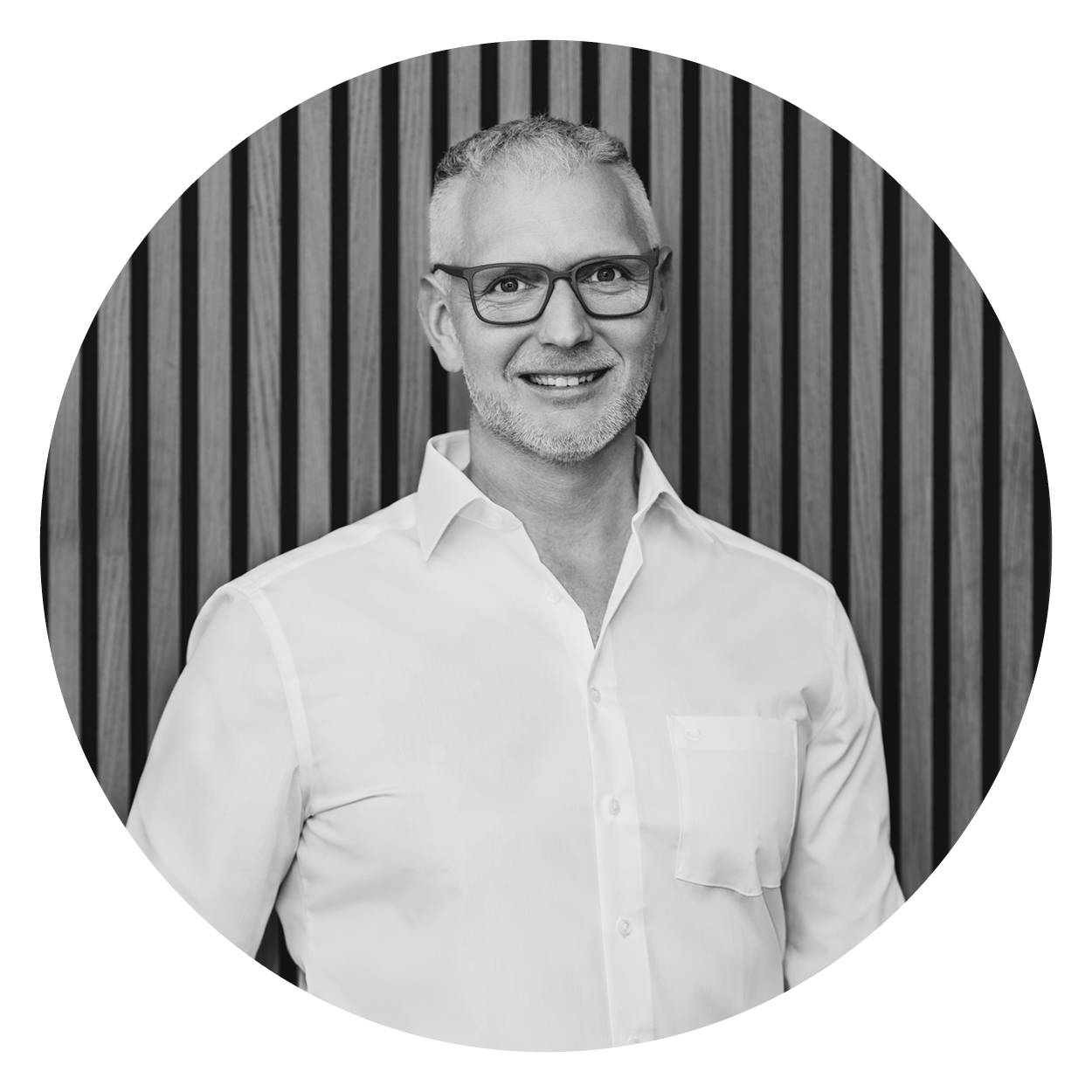 Person in einem weißen Hemd vor Holzwand, repräsentativ für das Team der Webschmiede WordPress Agentur, Oberwart.