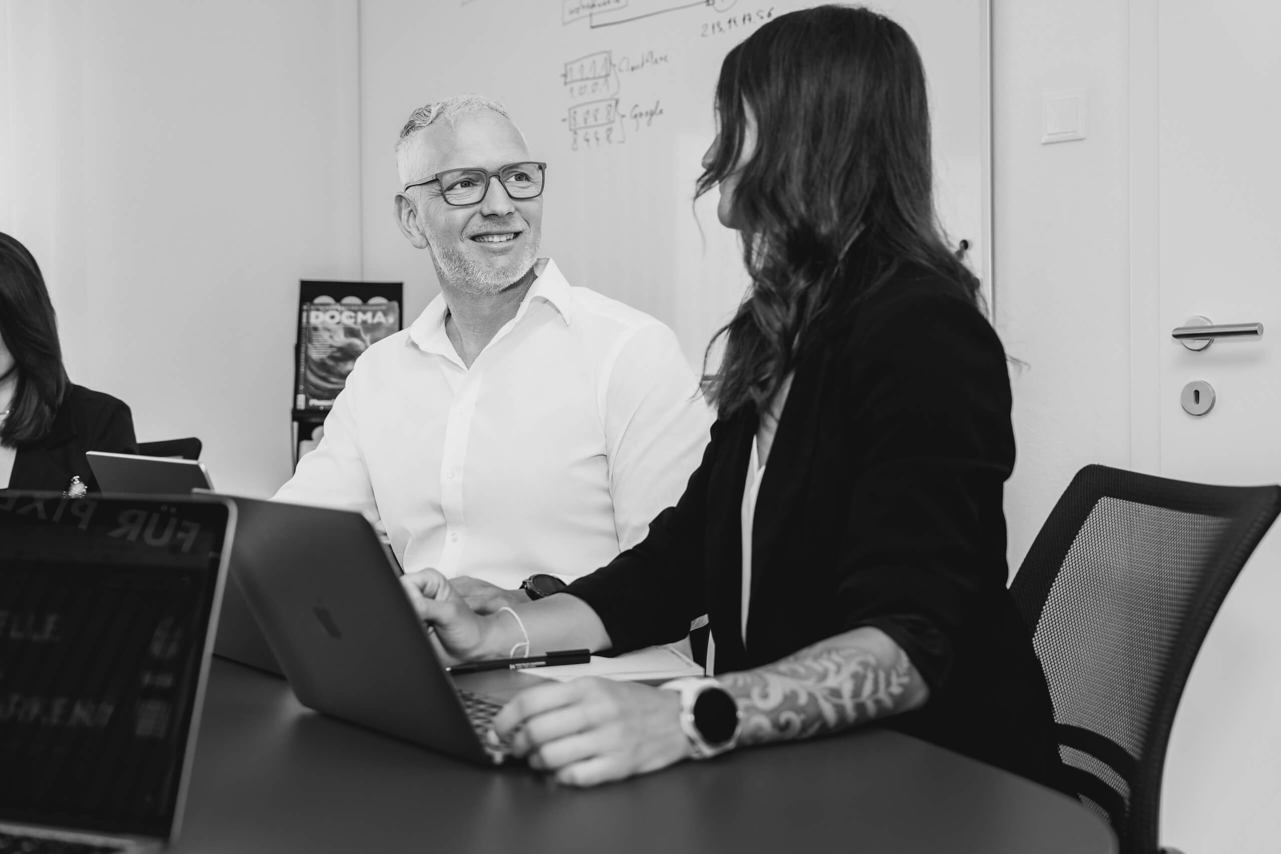 Team von Webschmiede bei der Arbeit an Laptops, bespricht WordPress-Projekte und SEO-Strategien für Websites.