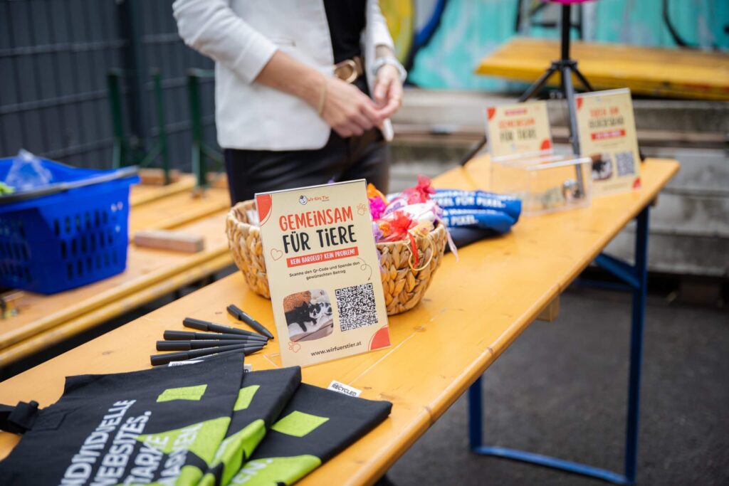 Spendenaktionstisch mit Flyer Gemeinsam für Tiere, QR-Code für Spenden, Körbe und Werbematerialien auf einem Holztisch.