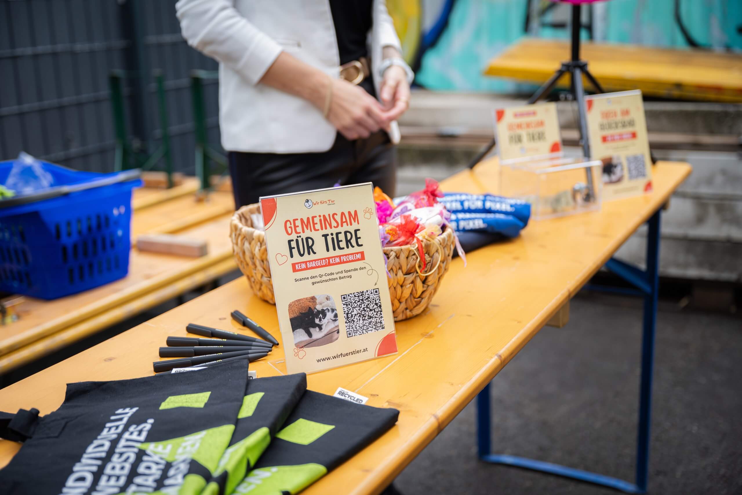 Spendenaktionstisch mit Flyer Gemeinsam für Tiere, QR-Code für Spenden, Körbe und Werbematerialien auf einem Holztisch.
